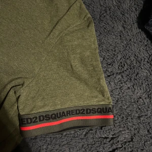 Dsquared2 tröja  - Säljer en olivgrön t-shirt från Dsquared2 med korta ärmar och en snygg detalj med logotypen på ärmslutet. T-shirten är tillverkad i bomull med en liten del elastan för extra komfort. 