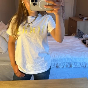 Vit vogue t-shirt - Säljer en vit vogue t-shirt med gult tryck framtill. .