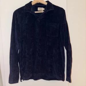 Mörkblå frottétröja från East West - Säljer en mörkblå frottétröja från East West med krage och en bröstficka. Tröjan har långa ärmar och är perfekt för en avslappnad stil. Den mjuka frottén ger en skön känsla.