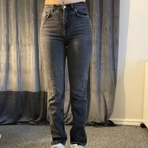 Mörkgrå jeans från Gina tricot - Snygga mörkgrå jeans från Gina tricot (premium denim) med en klassisk femficksdesign. De har en hög midja och en rak passform. Modellen är 167cm lång.