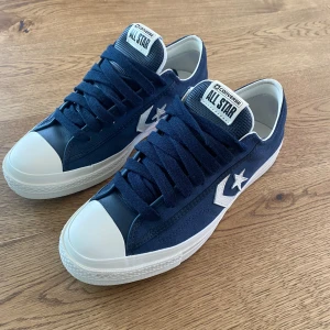 Blå Converse star player  - Snygga blå Converse All Star sneakers med vit sula och tåhätta. Skorna har klassisk snörning och det ikoniska stjärnlogotypen på sidan. Perfekta för en avslappnad stil. Skorna är sprillans nya aldrig använda säljer då dom är för små och inte går att retunera kan tänka mig att gå ner i pris vid smidig affär. Köptes för 1000kr och säljer för 600 då jag vill bli av med dom snabbt. Köparen står för frakt