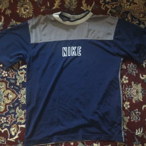 Blå och grå t-shirt från Nike - Säljer en blå och grå t-shirt från Nike med korta ärmar och ett klassiskt tryck på bröstet. Vintage stil med luftigt tyg står att den är xl med sitter som m