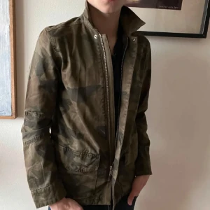 Camouflagejacka från Zadig & Voltaire - Snygg camouflagejacka från Zadig & Voltaire med dragkedja och krage. Jackan har en cool militärlook och är perfekt för en avslappnad stil. Den har praktiska fickor och är långärmad. Nypris ca 3500! Köpte den sprillans ny och har ej kommit till användning över vintern. Men blir perfekt nu när de börjar bli lite svalare!