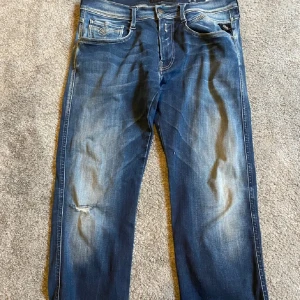 Replay jeans - Snygga blå jeansbyxor med en klassisk femficksdesign och lätt slitna detaljer. Byxorna har en rak passform och är perfekta för en avslappnad stil. De har en knappgylf och bälteshällor för extra funktionalitet.