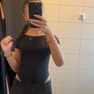 Svart kortärmad body - Säljer en stilren svart bod med korta ärmar och en djup öppen rygg. Aldrig använd, lappen kvar