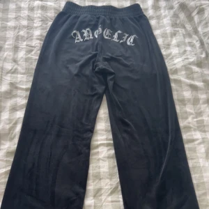 Svarta mjukisbyxor med tryck - Svarta mjukisbyxor med elastisk midja och tryck på baksidan. Perfekta för en avslappnad stil.