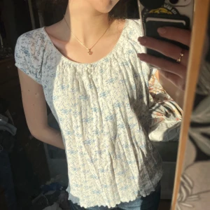 Söt blommig blus  - Söt blommig blus i ljusblått och vitt med korta ärmar. 