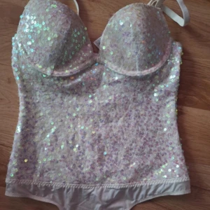 Glitter body - Säljer en glittrig vit korsett från La Senza med paljetter över hela ytan. Den har justerbara axelband och en bekväm passform. Perfekt för att lysa upp vilken outfit som helst! ✨