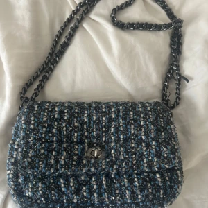 Becksöndergaard väska  - Snygg axelväska i blått och vitt med ett stilrent rutigt mönster. Väskan har en kedja som axelrem och ett praktiskt innerfack med dragkedja. Perfekt för att ge din outfit en trendig touch. Jätte fint skick