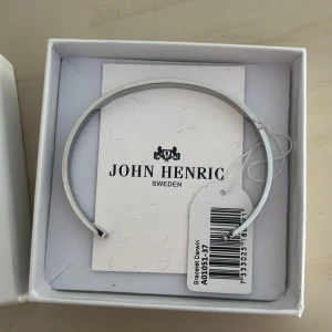 Silverfärgat armband från John Henric - Stilrent och minimalistiskt armband i silverfärg från John Henric, modell Darwin. Armbandet har en enkel och modern design med rundad form och levereras i original ask. Perfekt för dig som gillar clean och snygg stil. Helt ny aldrig använd, endast testat. Nypris 499kr