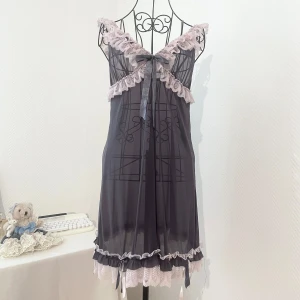 Mörkgrå spetsklänning med rosett - Supersöt mörkgrå kortklänning med transparent mesh och ljusrosa spetsdetaljer. Mycket genomskinlig, vilket passar perfekt till att matcha med andra plagg. Storlek: S (36), passar även 34 och 38. Dockans storlek: 34.