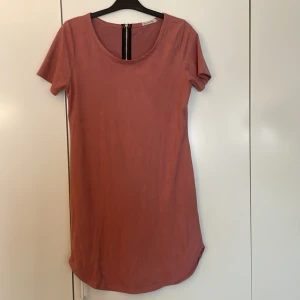 Rosa kortklänning från Heart vs Hips - Enkel och snygg rosa kortklänning från Heart vs Hips. Klänningen har rund halsringning, korta ärmar och en dekorativ dragkedja i ryggen. Materialet känns mjukt och följsamt, perfekt för en chill och stilren look.