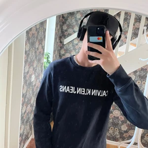 Svart sweatshirt från Calvin Klein Jeans - Svart sweatshirt från Calvin Klein Jeans i storlek M. Tröjan har en klassisk rund hals och vit logotyp framtill. Tillverkad i mjuk bomull, perfekt för chill dagar. Långärmad och med ribbade muddar vid ärmslut och nederkant. Snygg och enkel stil. Den passar perfekt nu till höst\vinter kontakta mig vid intresse Priset är inte hugget o sten och kan diskuteras