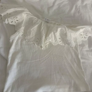 Vit offshoulder topp med volang  - Superfin vit one shoulder tröja