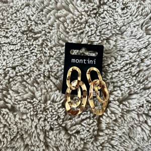 Guldiga örhängen från Montini💛 - Säljer ett par statement örhängen från Montini i guldigt metallmaterial. De har en cool länkdesign med en trendig vibe. Perfekta för att lyfta din outfit med lite extra bling. Aldrig använt, prislappen sitter kvar.