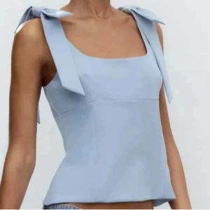 Ljusblå topp från Zara  - Supersöt ljusblå linnetopp med breda axelband med stora rosetter på axlarna. Toppen har en fyrkantig urringning och är figursydd för en snygg passform. Perfekt för en fräsch och trendig look. Endast använda 1-2 gånger så den är i väldrig bra skick. Storlek S🩵  