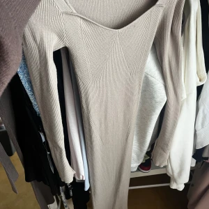 Beige ribbad långklänning Gina Tricot - Säljer en beige ribbad långklänning från Gina Tricot i storlek XS. Klänningen har lång ärm, v-ringad hals och är figurnära med snygga ribbade detaljer som ger en cool struktur. Perfekt för dig som gillar stilrena och enkla looks.