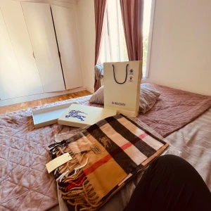 Rutig halsduk i kashmir från Burberry - Exklusiv halsduk från Burberry i 100% kashmir med klassiskt rutigt mönster i beige, svart, röd och vit. Mjuka fransar i ändarna och broderad Burberry-logga. Perfekt accessoar för att lyfta din outfit med lyxig känsla.