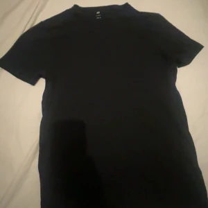 Svart t-shirt från H&M - Svart slimfit t-shirt från h&m. Både tjejer och killar kan använda och den är i nytt skick!
