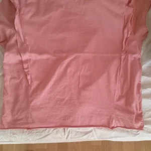 Rosa topp från Zara Trafaluc L - En enkel och snygg rosa topp från Zara Trafaluc, kollektion vår/sommar 2017. Modellen har korta ärmar och raka linjer med dekorativa sömmar längs sidorna. Tillverkad i mjuk bomull som känns skön mot huden. Perfekt för en chill och avslappnad look. Se bilder för storlek och skick. Osäker på storlek men det finns bild på storlekslappen. 