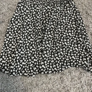Svart blommig kjol från 157 XS - Supersöt svart kjol med vita små blommor från 157 i storlek XS. Kjolen har en kort och flowy passform med resår i midjan som gör den bekväm och enkel att bära. Perfekt för dig som gillar blommigt och vill ha en chill look. Priset kan diskuteras mellan 15-25kr