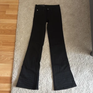 Svarta bootcut jeans Cheap Monday - Svarta bootcut jeans från Cheap Monday i modellen Bootybel. Byxorna har låg midja och är tillverkade i superstretchigt material för en bekväm passform. Klassisk femficksdesign och diskreta detaljer. Perfekta för dig som gillar en snygg siluett med utsvängda ben.