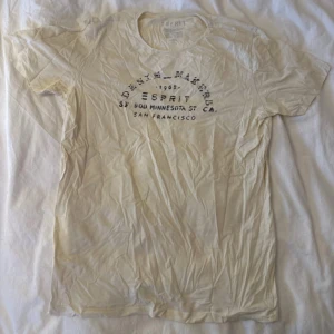 Vit t-shirt från Esprit med tryck - Vit t-shirt från Esprit med svart texttryck på bröstet som har en vintage San Francisco-vibe. Klassisk rund hals och korta ärmar. Mjuk bomullskvalitet som känns skön mot huden. Perfekt för chill dagar och enkel att matcha med jeans eller shorts.