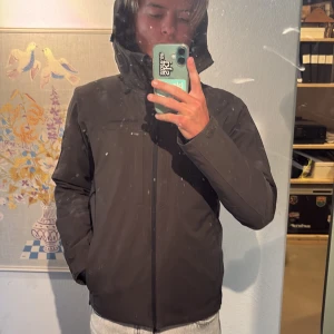 Mörkgrön dunjacka med skal från Peak Performance - Mörkgrön dunjacka med ett yttre skal från peak performance. Väldigt fint skick och går bra att använda både i vardagen och i skidbacken.