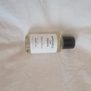 Mitchell and Peach Body Oil 50ml - En lyxig kroppsolja från Mitchell and Peach i en genomskinlig glasflaska med svart skruvkork. Innehåller 50 ml och är berikad med mandelolja och vitamin E för mjuk och väldoftande hud. Doft av citrus och blommor. Perfekt för dig som vill ha glow och återfuktning.