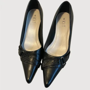 Svarta, spetsiga kitten heels med spänne - Så snygga, spetsiga kitten heels från märket Kit. Storlek UK 4, så ungefär storlek EU 37. De är ca 24 cm långa på insidan, från längst in vid tån till hälen. Lite slitna på klacken, men inget som syns mycket alls. 