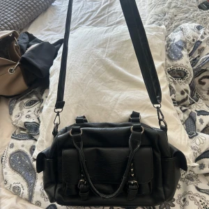 Svart väska med nitar - Jätte fin handväska med nitar och många fack. Har några trådar som sticker ut men annars inga defakter