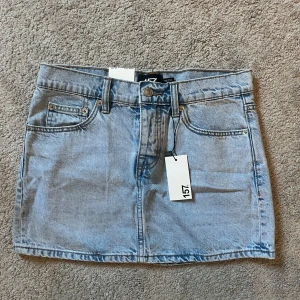 Jeanskjol  - Säljer en ljusblå jeanskjol från 157 i klassisk femficksmodell. Kjolen har knapp och dragkedja framtill, bälteshällor och två stora bakfickor. Perfekt för dig som gillar en enkel och snygg denimlook. (I nyskick)