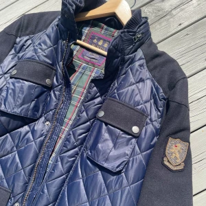 Morris Cardigan Jacka Blå - Snygg quiltad jacka från Morris i mörkblått med rutigt foder. Fåtal gånger använd och är i nästan nyskick. Storlek L. Extra knappar och extra luva finns med.