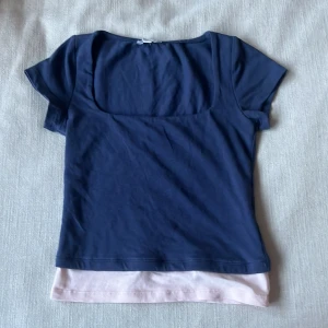 Subdued topp - En blå topp som har rosa längst ner i storlek S. Man kan vika upp den rosa bitten om man inte vill ha den.den är bara använd nån enstaka gång.