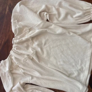 Vit blus med volang från Kappahl - Säljer en söt vit blus från Kappahl i storlek 170. Blusen har långärmade puffärmar och volangdetaljer längs halsringningen. Materialet är mjukt och har en lätt struktur som ger en chill vibe. Perfekt för dig som gillar romantiska detaljer och ljusa färger.