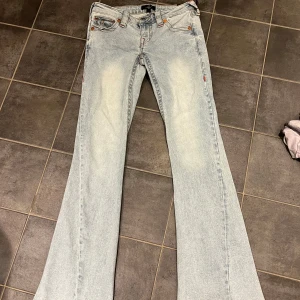 True Religion Joey ljusa flare jeans W24 - Säljer ett par True Religion Joey jeans i ljusblå, jätte low waist och flare/bootcut. Snygga broderade bakfickor med röd och gul detalj, jätte snygga och unika! De är helt nya med prislappen kvar och slutsålda på hemsidan!