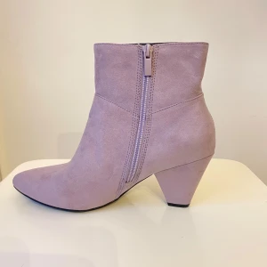 Ljuslila mocka stövletter med klack - Snygga ljuslila stövletter i mocka med spetsig tå och bred klack. Skorna har dragkedja på sidan för enkel påtagning och en stilren design som sticker ut. Perfekta för dig som vill addera lite färg till outfiten.