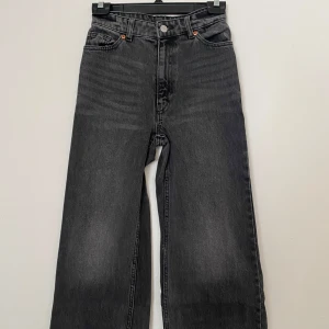 Gråa wide jeans från Monki - Snygga gråa jeans från Monki med hög midja och raka, vida ben. Jeansen har klassisk femficksdesign, silverfärgad knapp och Monki-logga bak i midjan. Perfekta för en chill och trendig look.