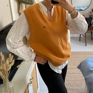Gul/orange stickad väst eller slipover  - Den här fina slipovern köpte jag på en second hand, men har aldrig använt. Den gula/orange färgen är perfekt i höst och gör sig snyggt över en vit skjorta. Jag är 172 cm och tror att plagget gör sig bäst på någon med storlek M-L.