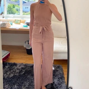 Puderrosa jumpsuit från zara - Superfin puderrosa jumpsuit i linneliknande material från zara! Halterneckmotell i halsen och låg i ryggen, knyts även med band i midjan. Den är även hellång i benen på mig som är 175 cm.