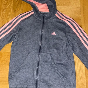 Adidas Tröja  - Säljer denna jättefina äkta Adidas ziphoodien/tröjan då den börjar bli för liten för mig och inte är min stil riktgt längre, den är köpt för 499kr online och är o storlek 140 men skulle nog mer säga att den motsvarar 146-152/xxs eftersom den ff passar mig som är en xs förutom att det saknar ca 5 cm i ärmarna köp för 200kr direkt eller buda från 150kr🤍 (i kommentarerna) 150kr inkl frakt skriv privat för frågor