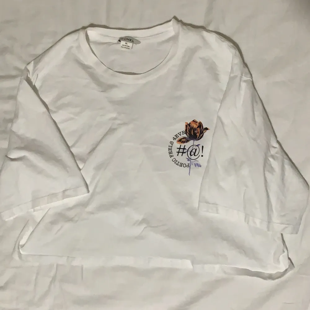 Croppad vit t-shirt från Monki med ett tryck på vänster sida. Använd men i fint skick. Du betalar priset (50kr)+frakt . T-shirts.