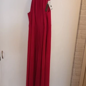 Strlk M - Oanvänd festklänning i fuschia färg. (Etiketten sitter kvar)   Det går bra att testa på sig hemma hos oss ifall ni önskar?