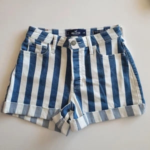 Shorts från hollister  - Vit och blå randiga shorts från hollister. Aldrig använda, lappen finns kvar. Ordinarie pris är 468 kr. Storleken är W 25. Det är knappjylf. Kan skicka med schenker så kostar frakten bara 56 kr. Köparen står för frakten. 