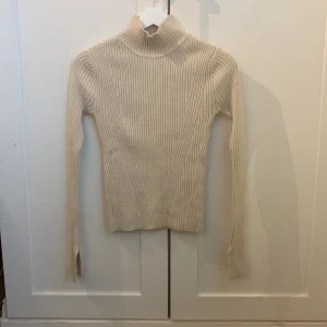 Stickad ribbad tröja i krämfärg - Väldigt fin passform, knappt använd! Storlek XS men passar S och M