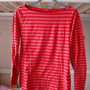 En långärmad tröja, med röda och rosa ränder. (Kontakta mig för frakt pris ).