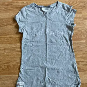 En grå t-shirt med ett vitt tryck i storlek XS