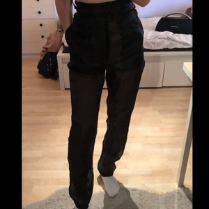 Genomskinliga byxor från nakd - Svarta genomskinliga byxor från nakd, endast testade, storlek 34, högmidjade samt framfickor, går att spänna med två spännen på sidorna, säljer pga att jag inte har så vågad stil och därmed kommer dom ej till användning, 100% polyester