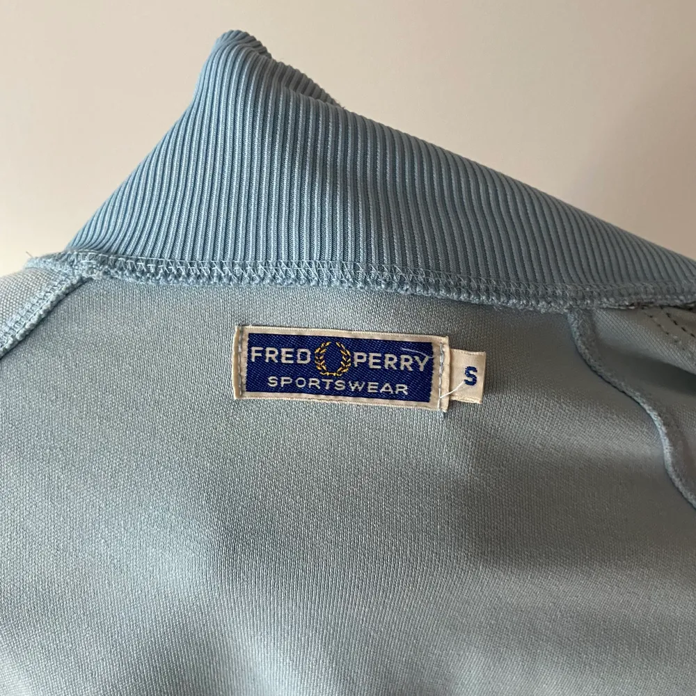 Vintage ljusblå Fred Perry tröja med blixtlås i storlek S. Sparsamt använd. Mycket fint skick.. Hoodies.