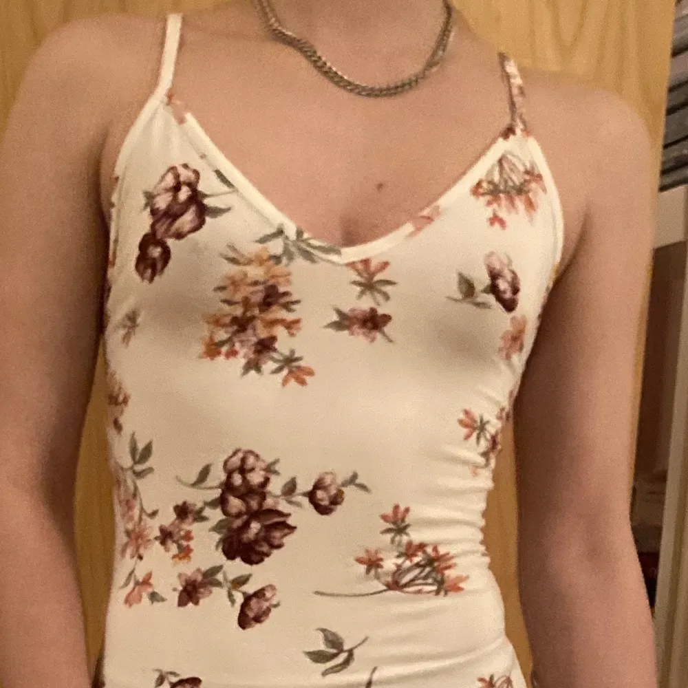 A white snug and stretchy dress that fits curves perfectly. Pretty pink flower patterns and an open back as well as a slit on the side. One size. Used only 2 times. . Klänningar.